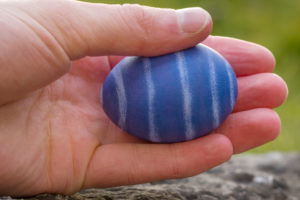 Hand holding blue and white striped Easter egg Hand holding blue and white striped Easter egg